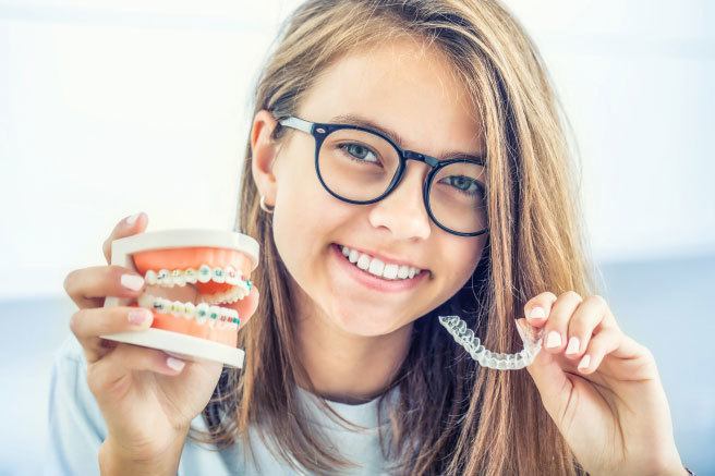 Smiling patient holding orthodontic dentures and retainer