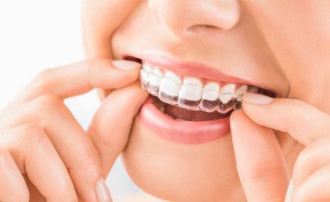 Smiling patient holding orthodontic dentures and retainer