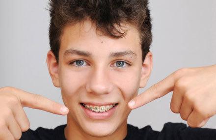 Smiling patient holding orthodontic dentures and retainer